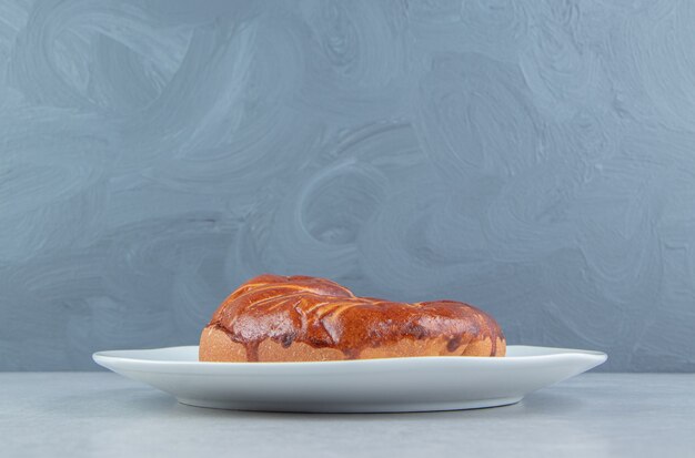 Hausgemachtes süßes Brötchen auf weißem Teller.