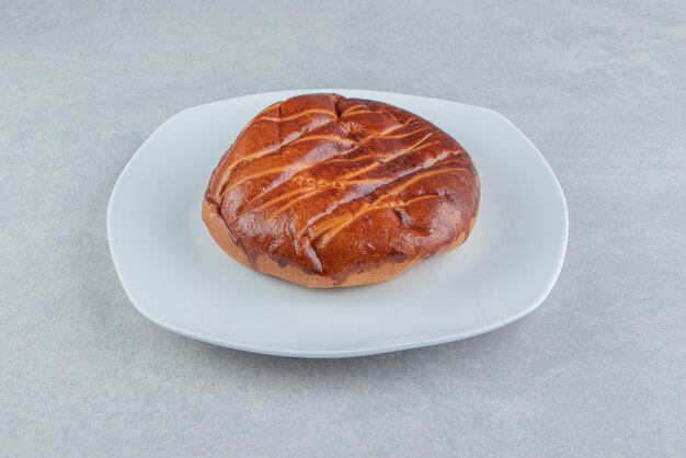 Hausgemachtes süßes Brötchen auf weißem Teller.