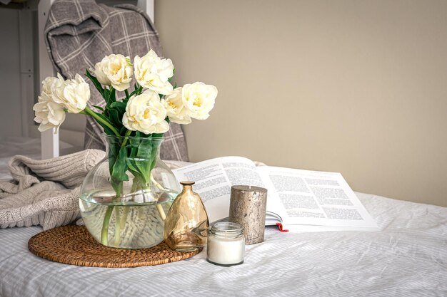 Hauskomposition mit einem Strauß Tulpen in einer Glasvase und Kerzen