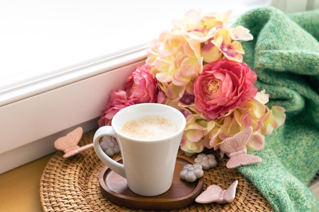 Hauskomposition mit einer Tasse Kaffeeblumen und einem gestrickten Element