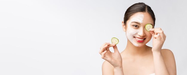 Hautpflegebild der jungen asiatischen Frauen der Schönheit mit Gurke auf weißem Hintergrundstudio