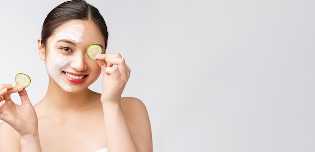 Hautpflegebild der jungen asiatischen Frauen der Schönheit mit Gurke auf weißem Hintergrundstudio