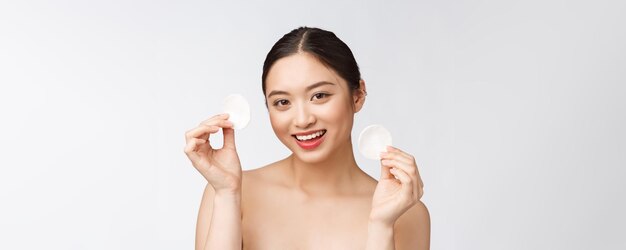 Hautpflegefrau, die das Gesichts-Make-up mit einem Wattestäbchen entfernt Hautpflegekonzept Gesichtsnahaufnahme eines schönen Mischlingsmodells mit perfekter Haut