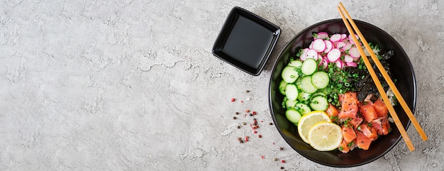 Hawaiian Lachs Fisch Poke Bowl mit Reis, Radieschen, Gurke, Tomate, Sesam und Seetang. Buddha-Schale. Diätessen. Draufsicht. Flach liegen