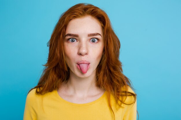 Headshot Portrait von glücklichen Ingwer rote Haare Mädchen mit lustigen Gesicht Blick in die Kamera. Pastell blauen Hintergrund. Text kopieren