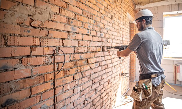 Heimwerker auf einer Baustelle beim Bohren einer Wand mit einem Perforator.