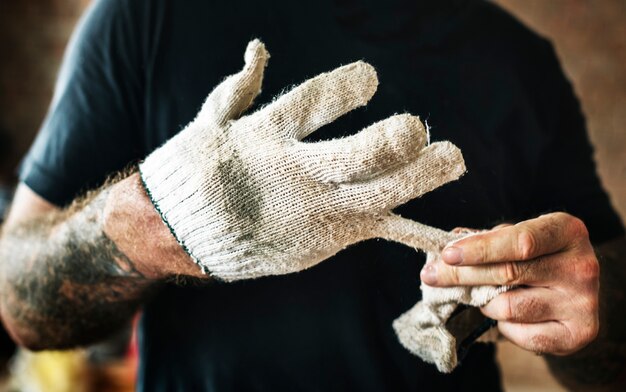 Heimwerker mit der Tätowierung, die einen Handschuh auszieht