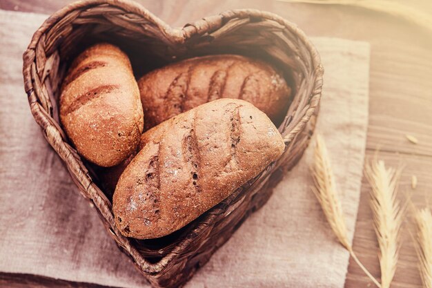 Heiße frische Brötchen in einem herzförmigen Korb. Nahaufnahme von frisch gebackenen Brotprodukten.