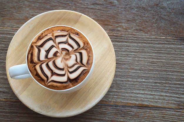 Kostenloses Foto heiße kaffeetasse der weinlese mit netter latte-kunstdekoration auf alter hölzerner beschaffenheitstabelle