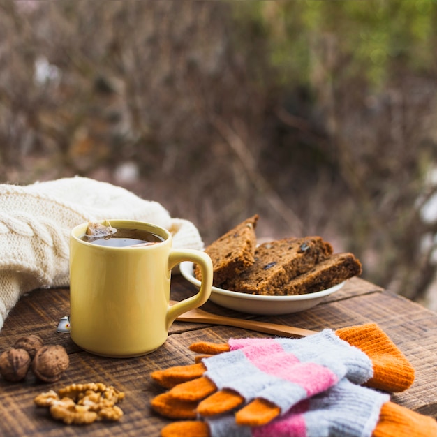 Heißer Tee und Dessert in der Nähe von Pullover und Handschuhe