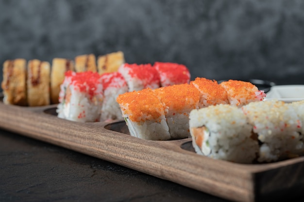 Heißes Sushi auf einem Holzbrett mit gemischten Zutaten.
