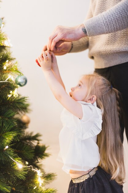 Helfende Tochter des Vaters, die belichteten Weihnachtsbaum verziert