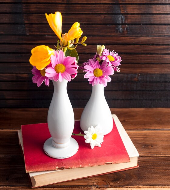 Helle Blumen in zwei Vasen auf Buch