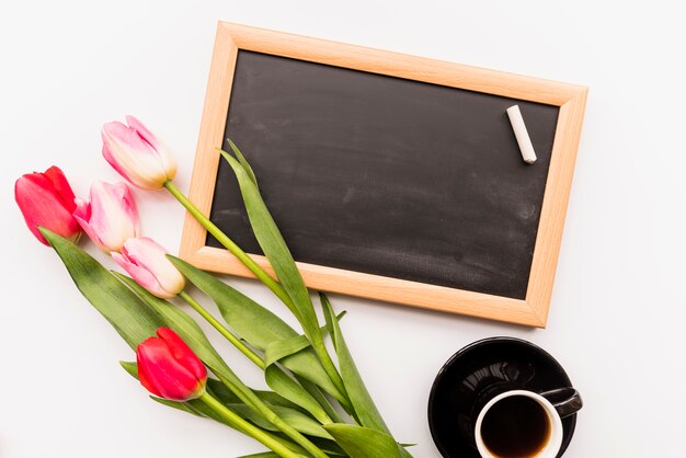 Helle frische Blüte auf Stielen in der Nähe von Tafel und Tasse Getränk