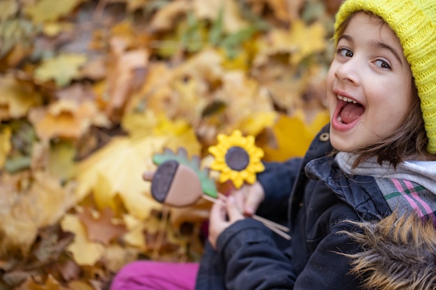 Helle handgemachte Lebkuchen im Herbst auf Stöcken in den Händen eines Kindes für einen Spaziergang im Herbstwald.