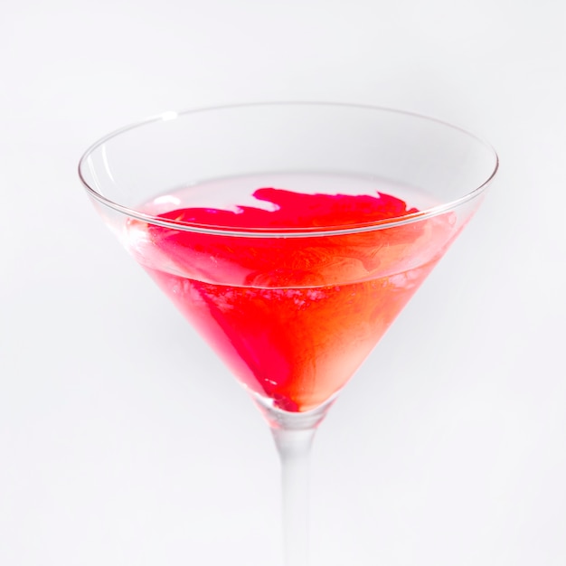 Helle rote Farbe lösen sich im transparenten Martini-Glas auf, das auf weißem Hintergrund lokalisiert wird