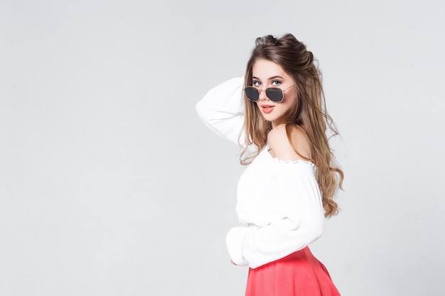 Helles positives Mode-Studio-Porträt eines jungen Mädchens mit nackten Lippen, das ein stilvolles, trendiges Outfit aus rosafarbenem Rock Smart Casual macht