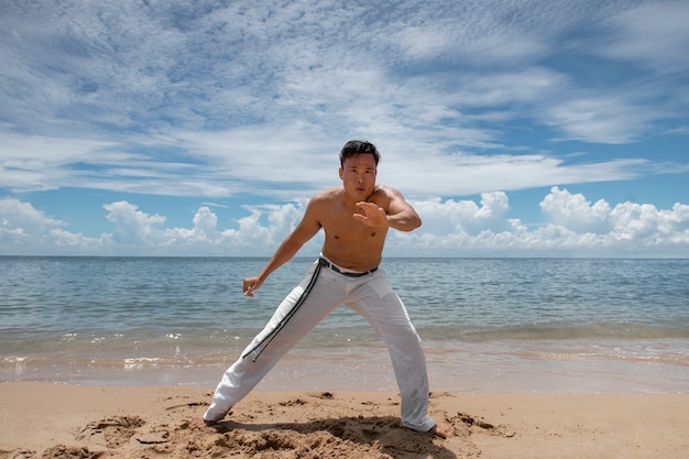 Kostenloses Foto hemdloser mann, der capoeira am strand praktiziert