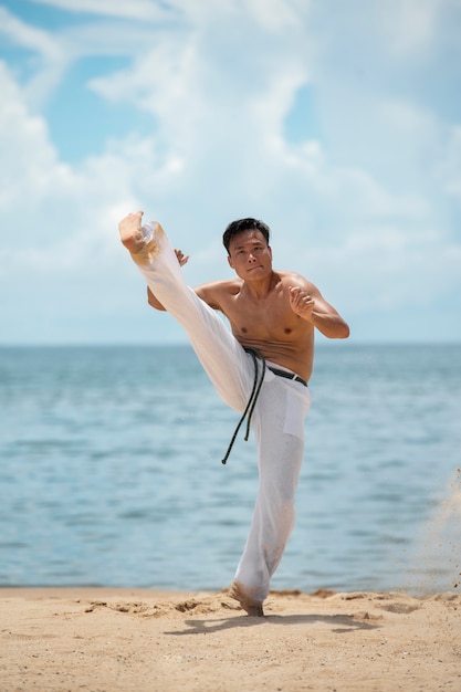 Kostenloses Foto hemdloser mann, der capoeira am strand praktiziert