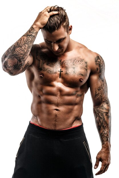 Hemdloser muskulöser tätowierter Mann lokalisiert auf weißem Hintergrund.
