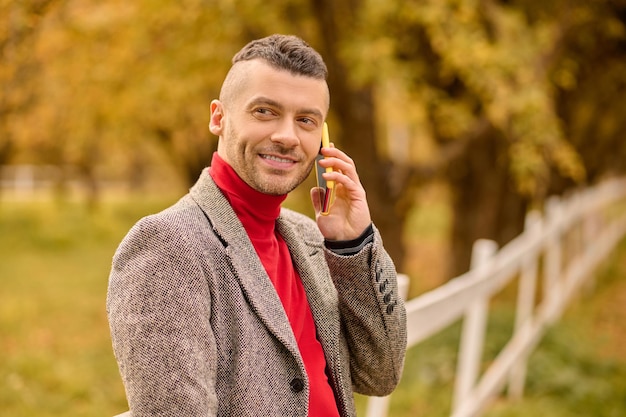 Herbst. Ein Mann mit einem stylischen Haarschnitt auf dem Hintergrund gelber Blätter