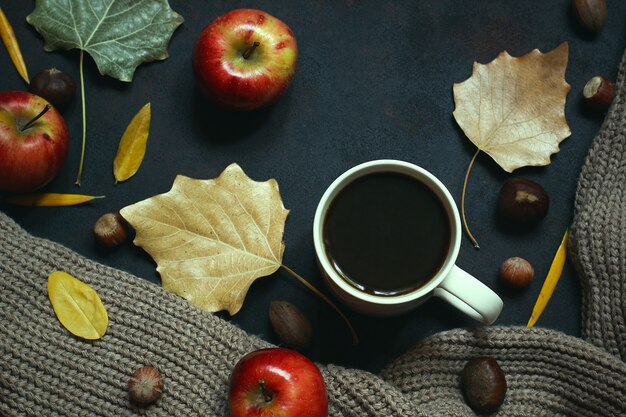 Herbst, Herbstlaub, heißer dampfender Kaffee und ein warmer Schal oder eine Strickjacke. Saison-, Morgenkaffee, Sonntag entspannend und Stilllebenkonzept.