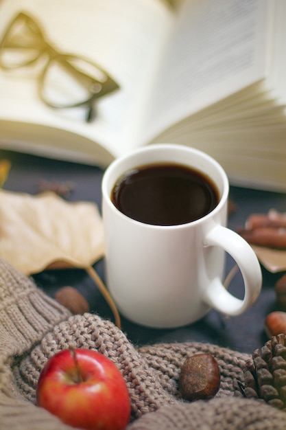 Herbst, Herbstlaub, heißer dampfender Kaffee und ein warmer Schal oder eine Strickjacke. Saison-, Morgenkaffee, Sonntag entspannend und Stilllebenkonzept.