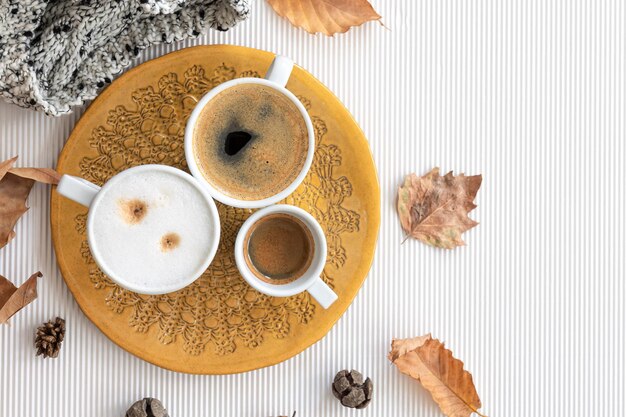 Herbstkomposition mit Tassen Kaffee und Blättern auf weißem Hintergrund