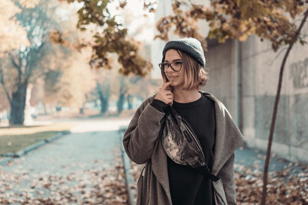 Herbstporträt im Freien der jungen Frau, die in der Straße der europäischen Stadt geht.