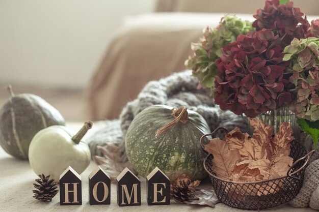 Herbststillleben mit Kürbissen, Herbstblättern und Hortensienblüten auf unscharfem Hintergrund. Das Konzept des Herbstkomforts zu Hause.