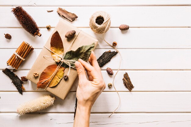 Herbstzusammensetzung mit der Hand, die Seil vom Geschenk hält