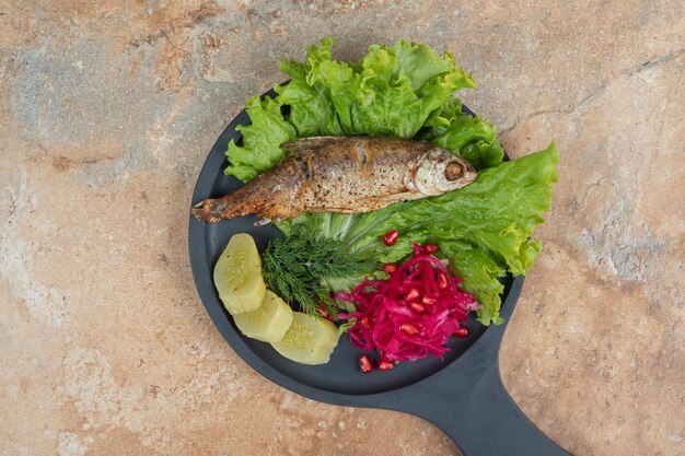 Hering mit Salat und Rotkohl auf Holzbrett