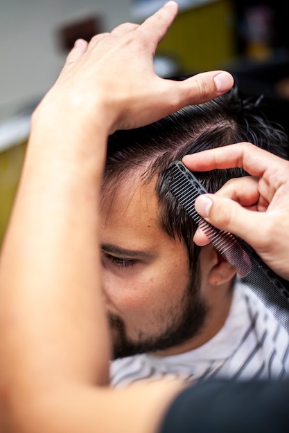 Kostenloses Foto herrenfriseur, der hohe ansicht des kundenhaares kämmt