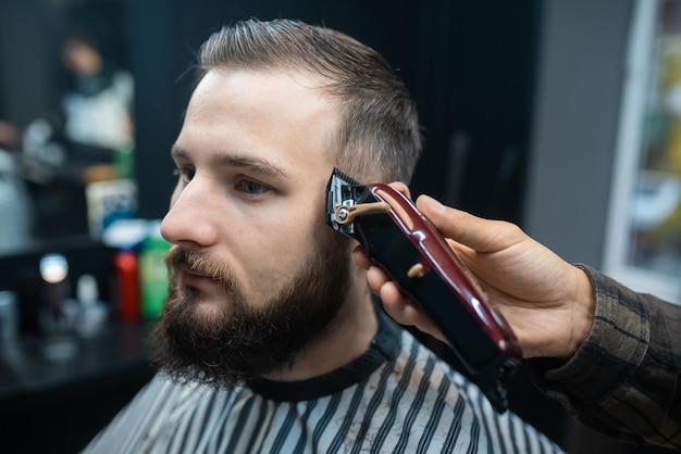 Herrenfriseur und Haarschnitt mit Haarschneidemaschine in einem Friseurladen oder Friseursalon