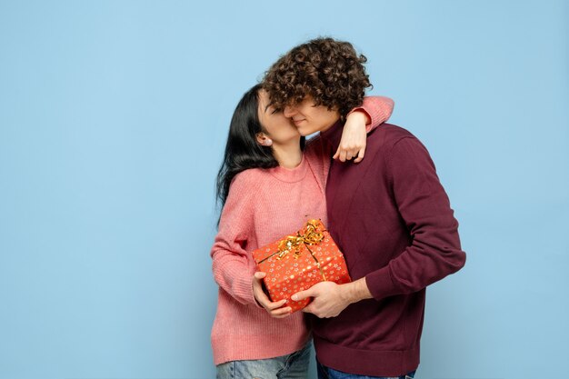 Herzballon, umarmend. Schönes Paar in der Liebe auf blauem Studiohintergrund. Valentinstag, Liebe, Beziehung und menschliches Gefühlskonzept. Copyspace. Junger Mann und Frau sehen glücklich zusammen aus.