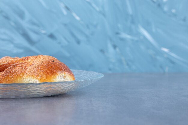 Herzförmiges Brötchen auf der Glasplatte auf Marmortisch.