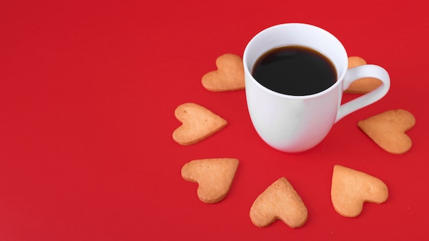 Herzplätzchen mit weißer Kaffeetasse auf Tabelle