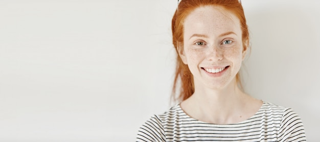 Heterochromie-Konzept. Attraktive junge Frau mit Ingwerhaar und verschiedenfarbigen Augen, die glücklich lächeln, isoliert posieren