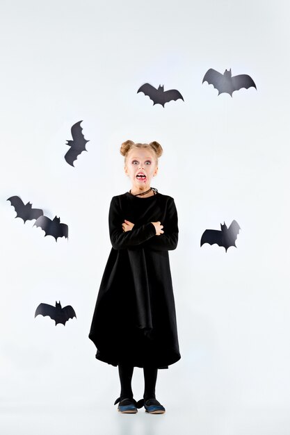 Hexe des kleinen Mädchens im schwarzen langen Kleid und in den magischen Accessoires. Halloween