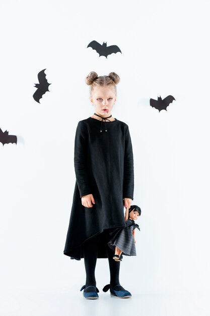 Hexe des kleinen Mädchens im schwarzen langen Kleid und in den magischen Accessoires