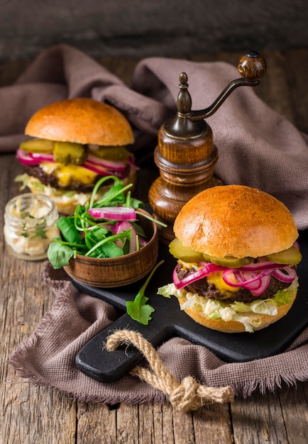 Kostenloses Foto high angle burger mit gurken und roten zwiebeln auf schneidebrett