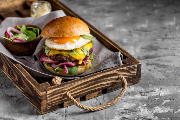 High-Angle-Cheeseburger mit gebratenen Eiern auf dem Tablett