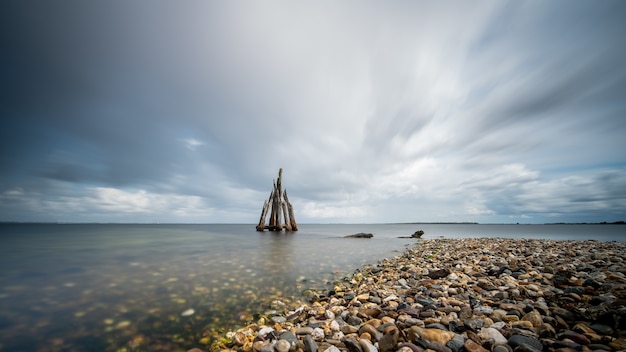 High Angle Closeup Schuss von Steinen an der Küste, die zum ruhigen Meer führen