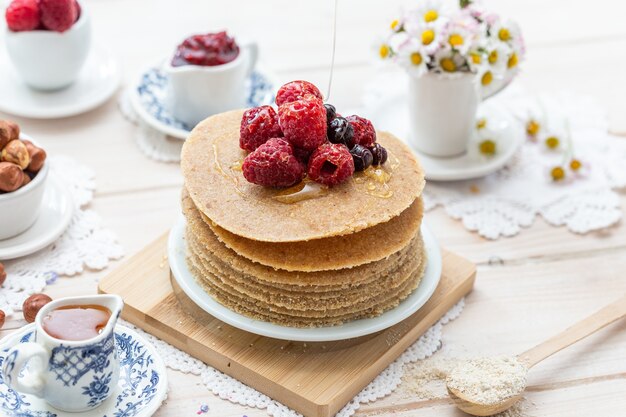 High Angle Closeup Shot von rohen veganen Pfannkuchen mit Honig und Beeren