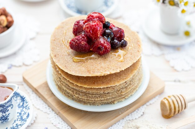 High Angle Closeup Shot von rohen veganen Pfannkuchen mit Honig und Beeren