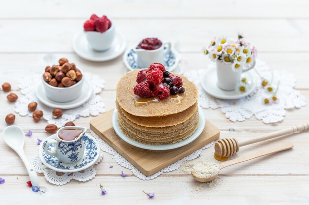 High Angle Closeup Shot von rohen veganen Pfannkuchen mit Honig und Beeren