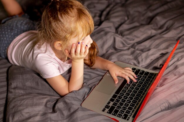 High Angle Girl auf dem Laptop im Schlafzimmer