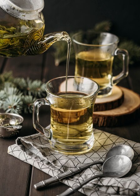 High Angle Hand gießt Tee in Glas mit Teekanne