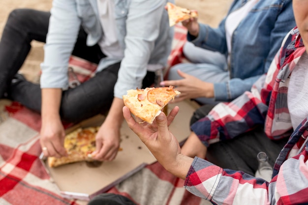 High Angle Leute nehmen ein Stück Pizza