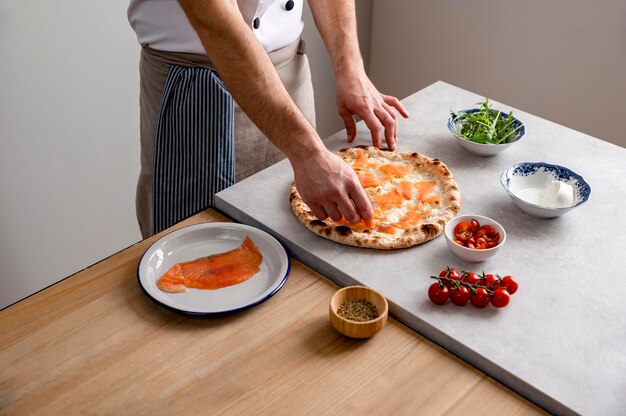 High Angle Man setzt geräucherte Lachsscheiben auf gebackenen Pizzateig